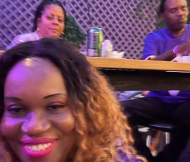 A moment of joy during the Purple Rain 40th bash — good vibes and even better company. Woman smiling in front of two seated guests during Purple Rain 40th anniversary celebration