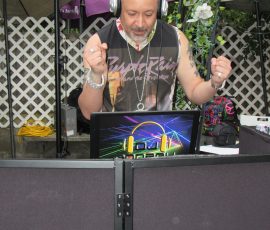 Beats by Prince, spun with love — the soundtrack of our 40th anniversary gathering. DJ wearing Purple Rain shirt spinning music behind console at outdoor Prince tribute